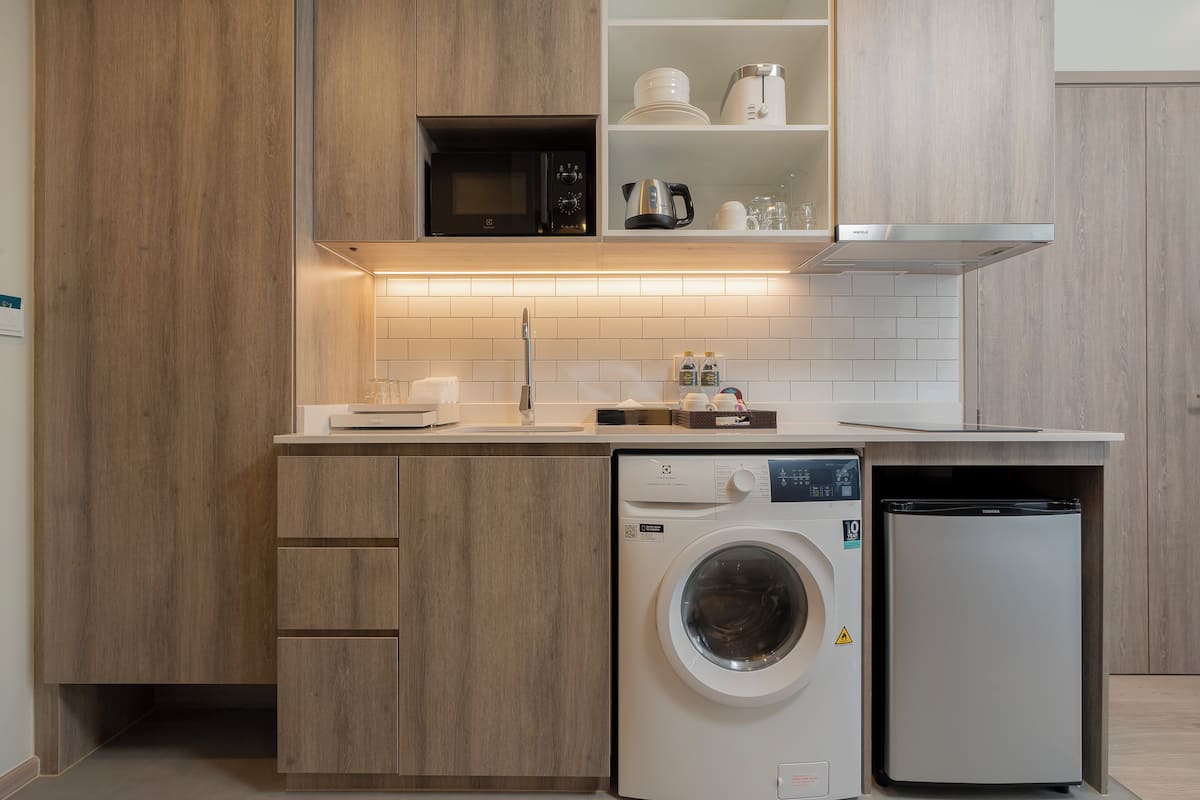 Una cocina compacta con muebles de madera, microondas integrado, lavavajillas y refrigerador.
