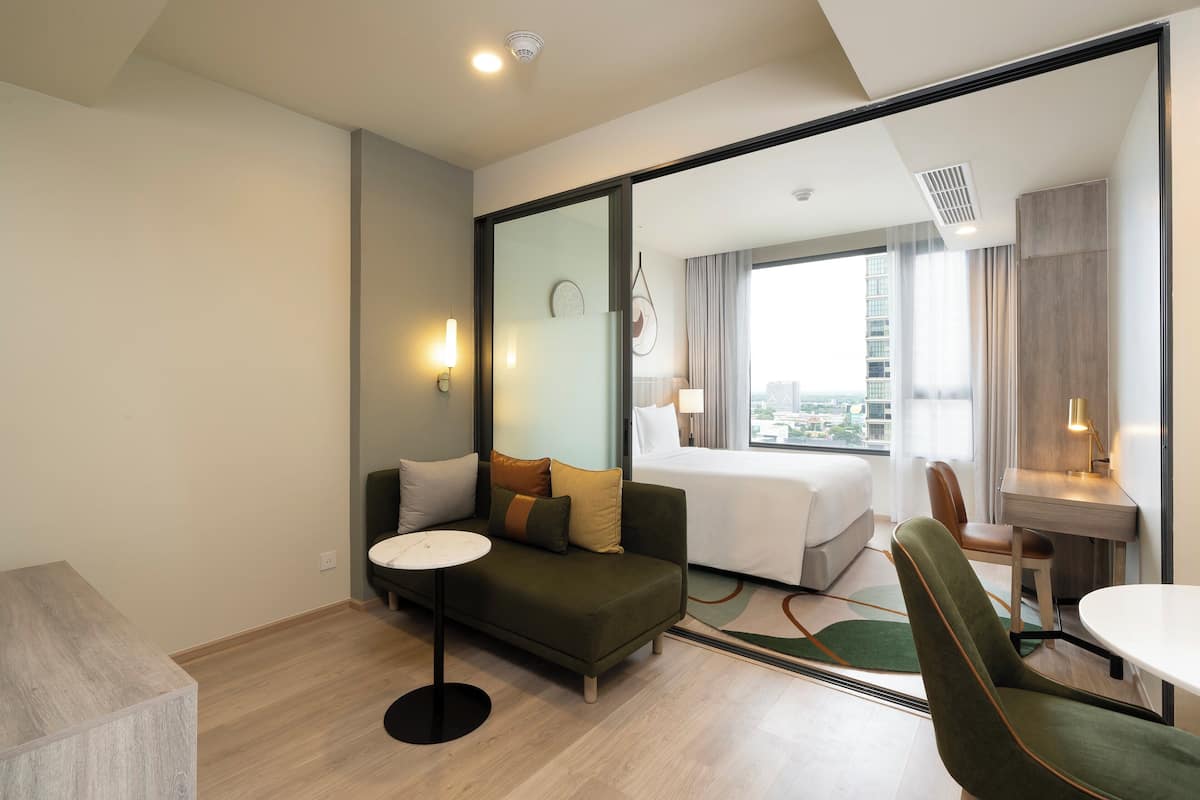 Une chambre d’hôtel moderne équipée d’un canapé, d’une petite table, d’un bureau et d’un lit.