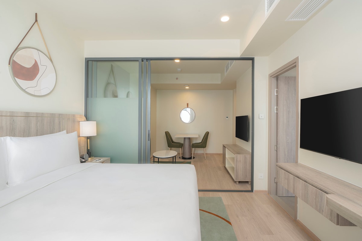 Une chambre d’hôtel avec un lit, un bureau, une chaise, une télévision et un miroir.