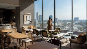 A modern interior with large windows, a city view, and a mix of seating and tables.