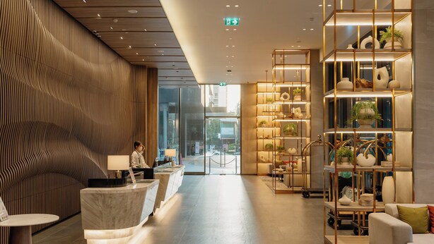 A modern lobby with a reception desk, seating area, and a plant display.
