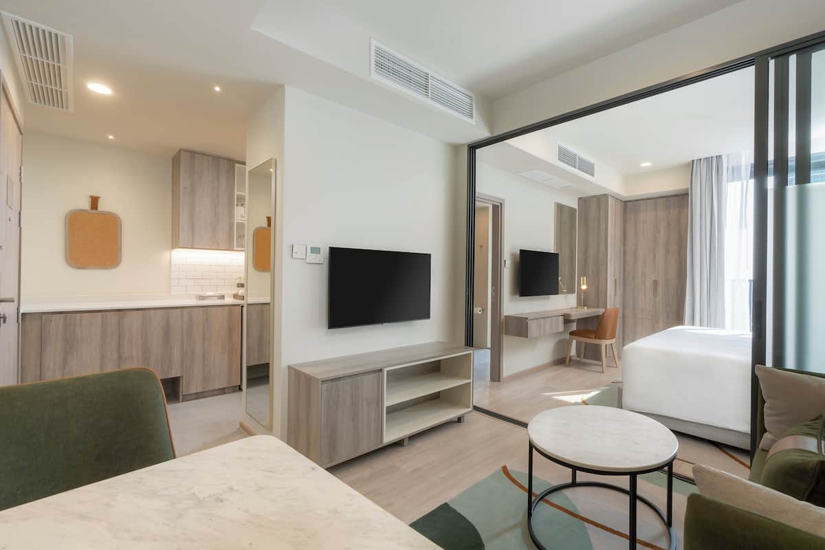 Une chambre d’hôtel moderne équipée d’un téléviseur à écran plat, d’un lit, d’un coin repas et d’une petite kitchenette.