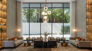 A modern living room with a large window, a central coffee table, sofas, and a decorative light fixture.