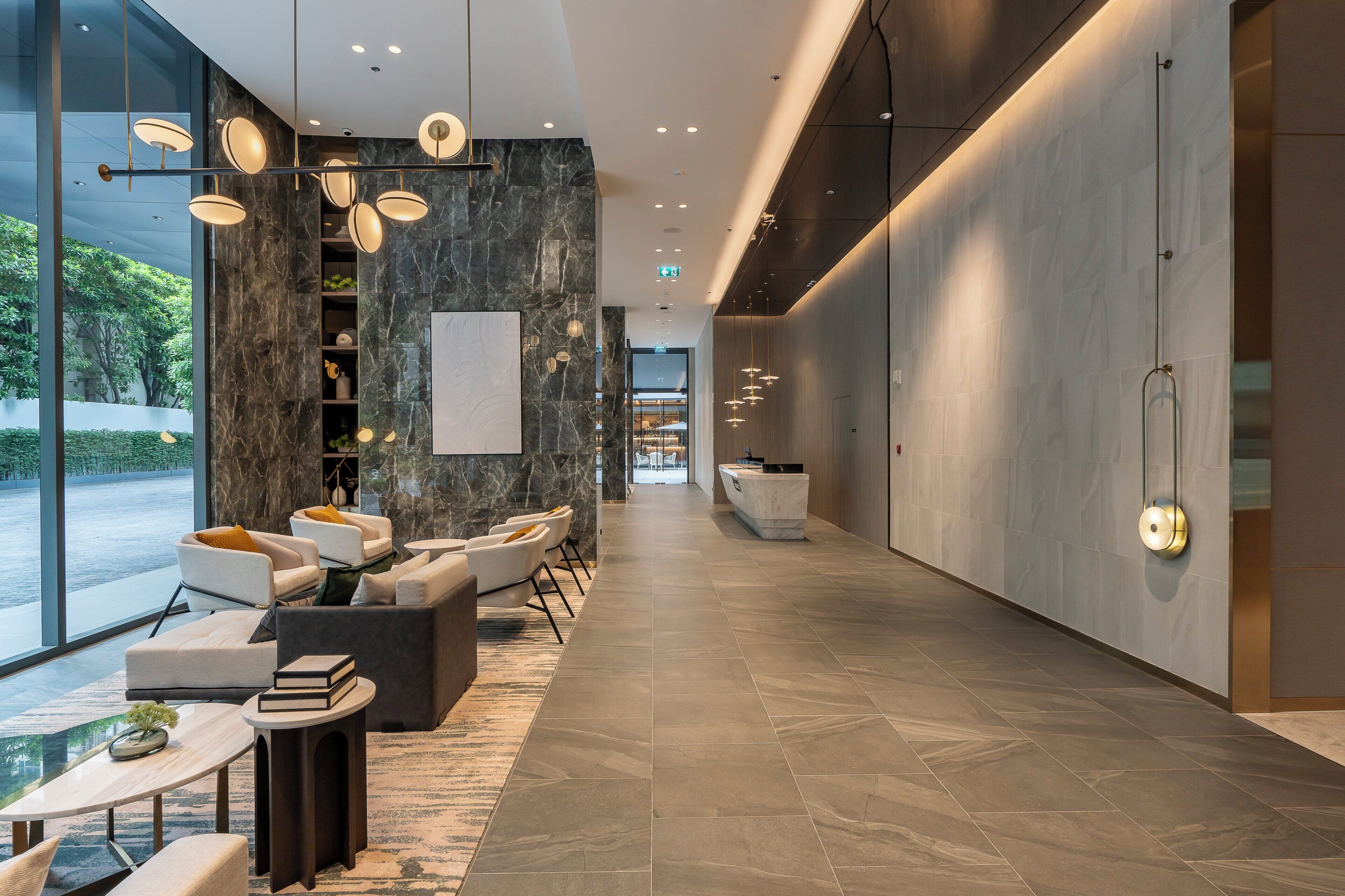 A modern hotel lobby with seating, a reception desk, and a view of the outdoors.