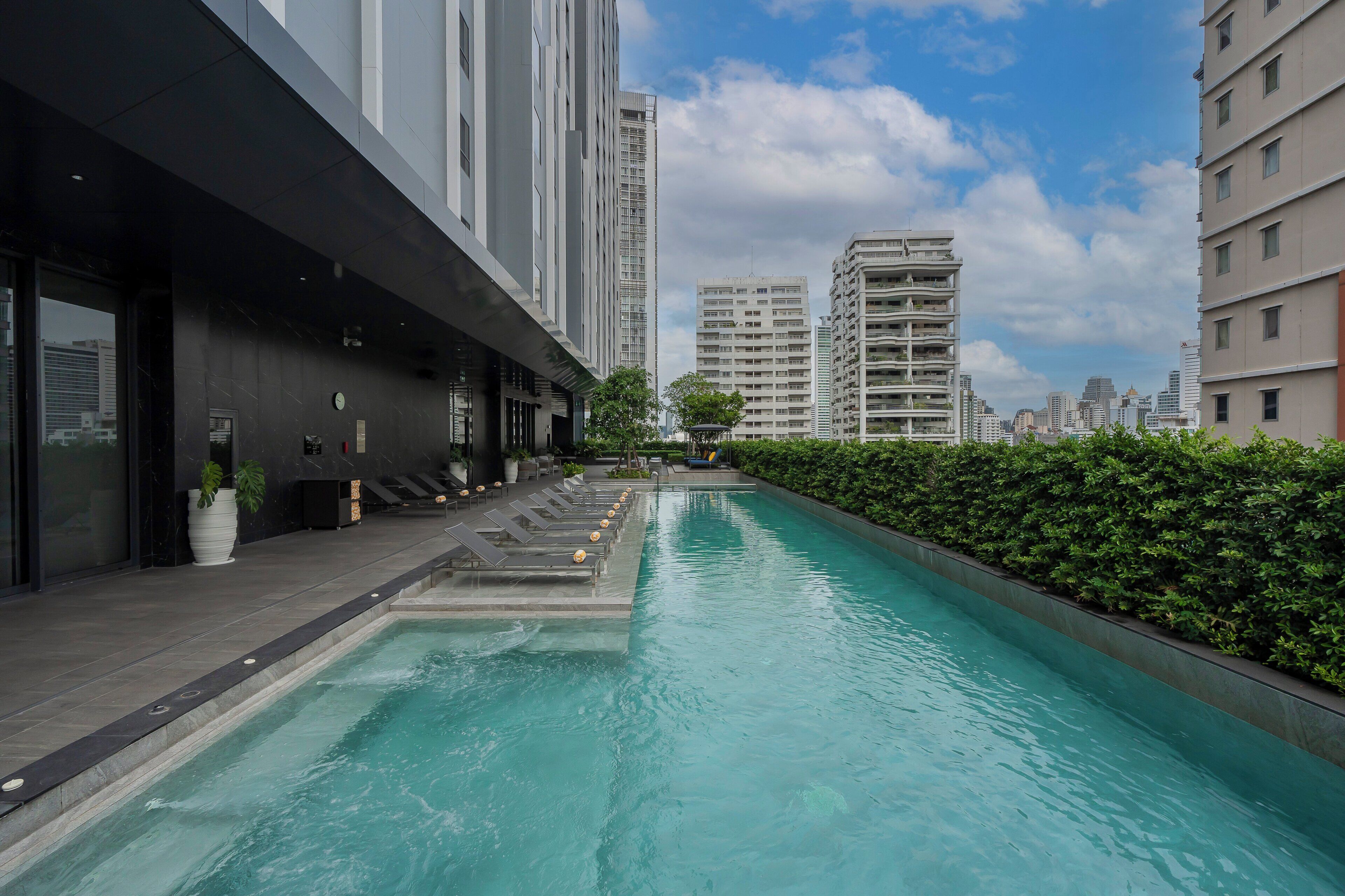 A swimming pool with lounge chairs and a view of high-rise buildings.