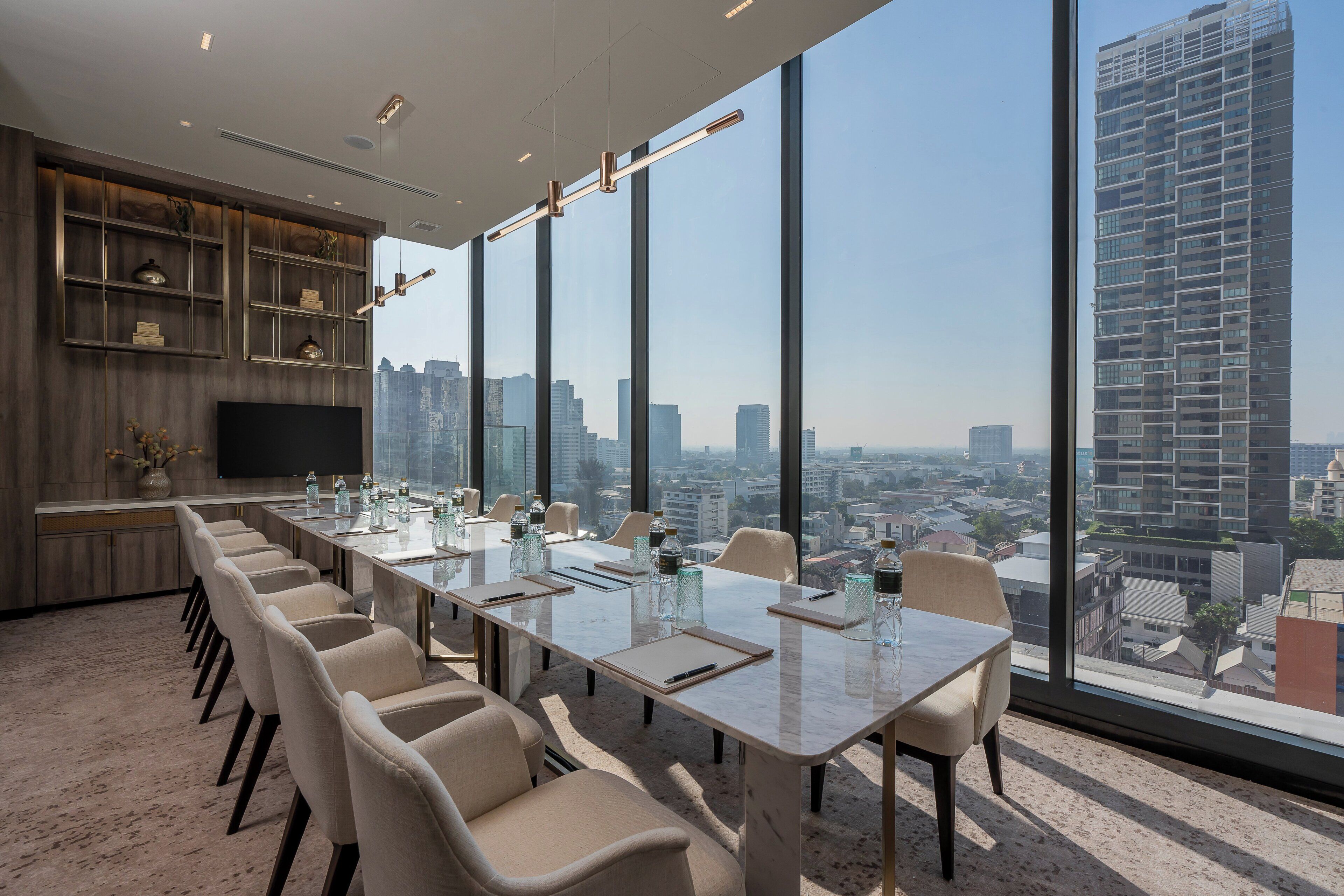 A modern conference room with a long table, chairs, and a city view.