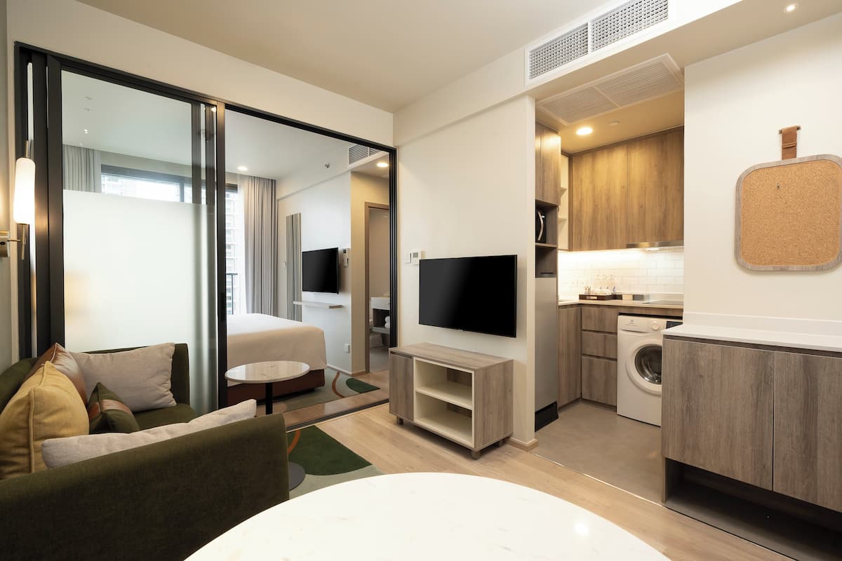Une chambre d’hôtel moderne équipée d’un canapé, d’une télévision, d’un lave-linge et d’une kitchenette.