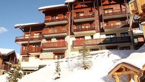 Un edificio in legno a più piani con balconi, circondato dalla neve.