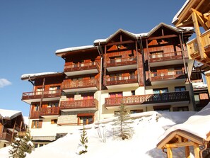 A multi-story wooden building with balconies, surrounded by snow.