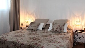 A bedroom with a floral bedspread, two bedside lamps, and a curtain on the window. - Modern Apartment, Sleeps 4, Air-Conditioned with Parking (Villeneuve-Loubet)
