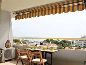 Un balcon avec une table et des chaises, une vue sur un port de plaisance et un bâtiment en arrière-plan.