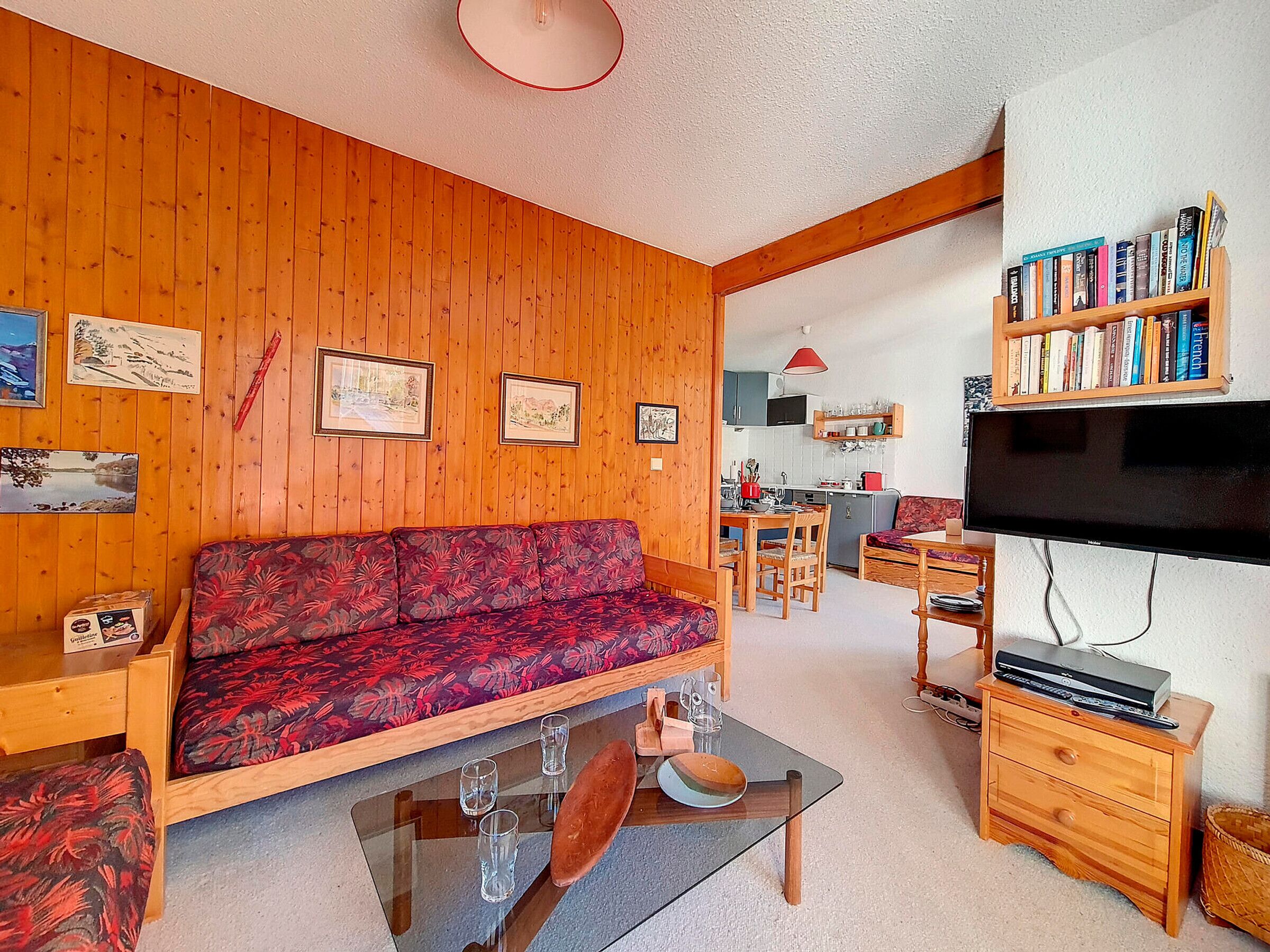 A cozy living room with a wooden wall, a sofa, a coffee table, and a bookshelf.