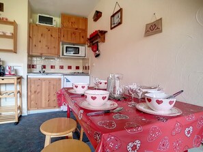 Cozinha com armários de madeira, micro-ondas e mesa de jantar posta com louças de corações.