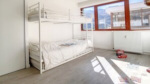 Een slaapkamer met stapelbedden en uitzicht op bergen door een groot raam.