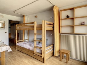 A bunk bed room with a wooden floor, a small table, and a radiator.