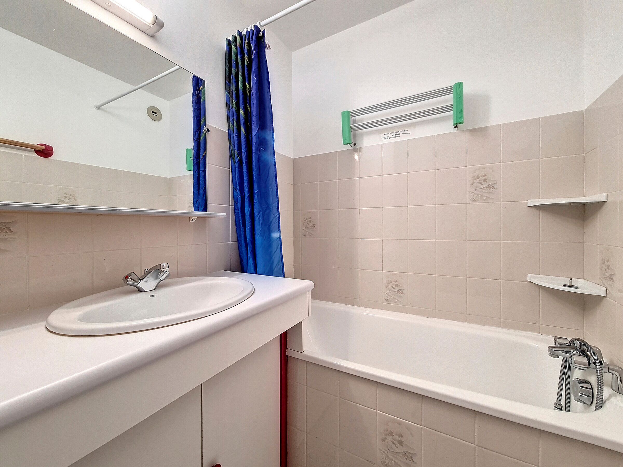 A bathroom with a white sink, a mirror, a bathtub, and a shower curtain.