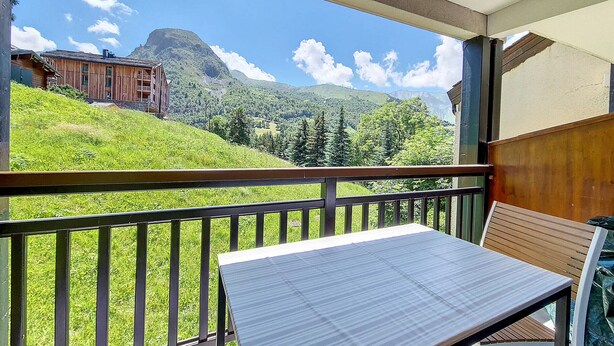 A balcony with a view of a mountain and a wooden building.