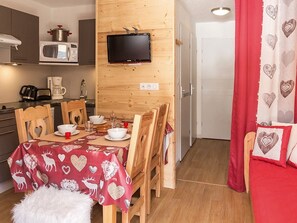 A compact kitchen with a microwave, stove, and a flat-screen TV mounted on the wall. - Cozy apartment with terrace - Ski-in/ski-out (Les Menuires)