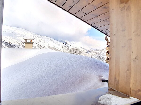 A snowy landscape with a wooden structure, possibly a cabin or lodge, with a snow-covered roof and a wooden floor.