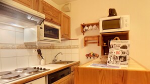 Uma cozinha compacta com armários de madeira, fogão, micro-ondas e lava-louças.