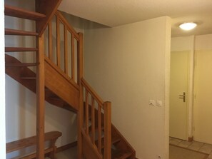 A wooden staircase leading to an upper floor, a white door, and a light switch on the wall.