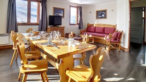 Una habitación amplia con una mesa de madera para comer, sillas, un sofá y una televisión.