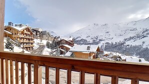 Un pintoresco pueblo de montaña nevado con edificios de madera y un coche rojo estacionado en una carretera cubierta de nieve.