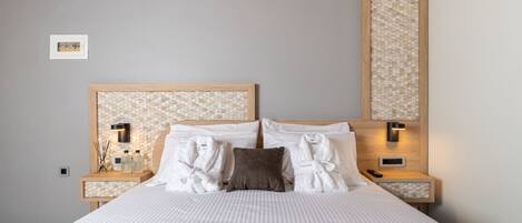 A neatly made bed with white linens, a headboard with a mosaic pattern, and two bedside tables with lamps.