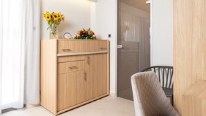 A room with a wooden cabinet, a vase with flowers, a clock, and a chair. - Metropolitan Pearl Hotel (Chania)