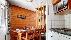 A compact kitchen with wooden walls, a dining table with chairs, and a microwave above the counter. - Charming duplex 6 pers, near slopes, north balcony, WiFi (Les Menuires)