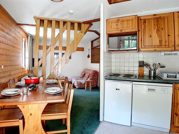 Un interior de madera con comedor, cocina y escalera.