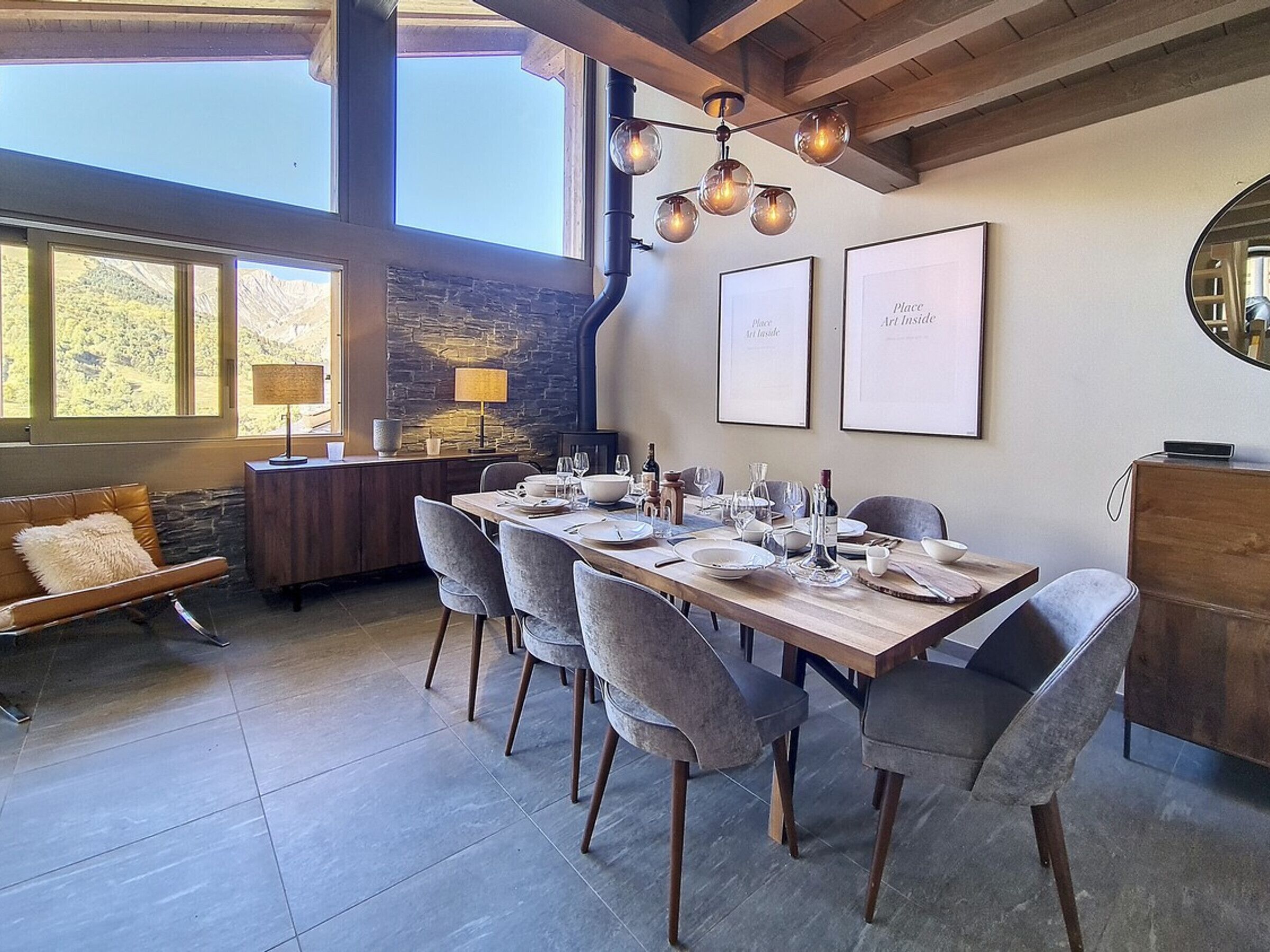 Uma sala de jantar com uma mesa comprida posta para seis pessoas, rodeada por cadeiras estofadas cinzas.