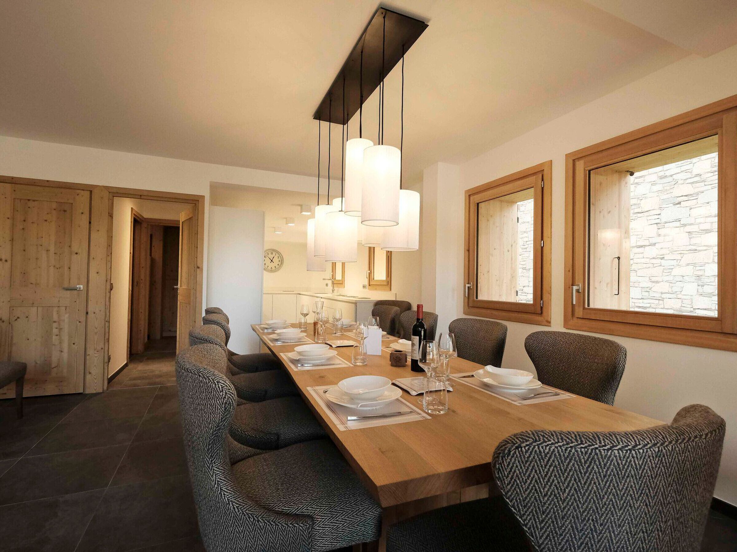 A dining area with a long wooden table set for six, surrounded by patterned chairs.
