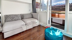 Ein modernes Wohnzimmer mit einem grauen Sofa, einem Glastisch und einem blauen Sitzsack.