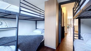 Ein Schlafraum mit Etagenbetten, einem Holzschrank, einem Schreibtisch und einem Stuhl.