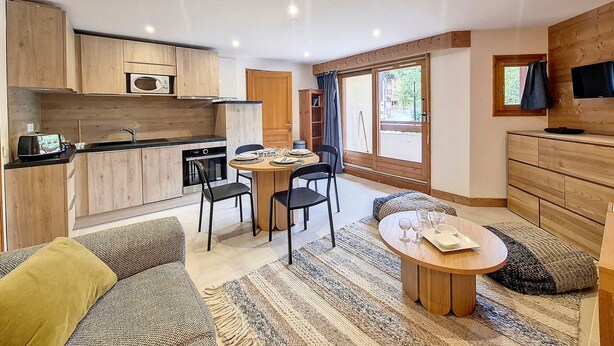 Een kleine leefruimte met een kitchenette, een eethoek en een zithoek.