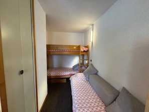 Ein kleines Zimmer mit Stockbetten und einer Schlafcouch.