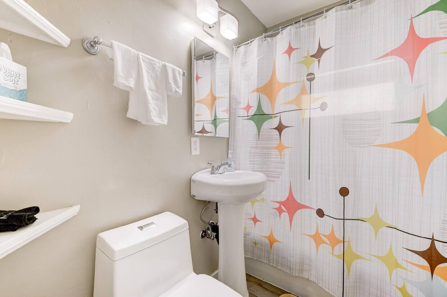 A bathroom with a toilet, sink, and shower curtain with a star pattern.