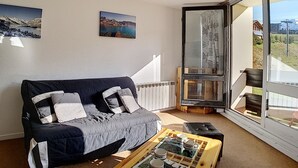 Un soggiorno moderno con un divano grigio, un tavolino in legno e un'ampia finestra con vista sul paesaggio costiero.