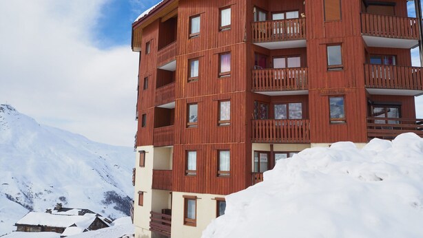 Ein mehrstöckiges Holzgebäude mit Balkonen, umgeben von Schnee und Bergen.