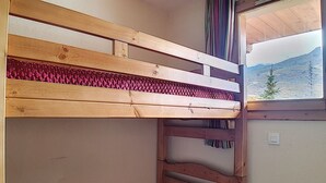 A bunk bed with a red mattress and a view of a mountain through a window. - 2-room apt 4 pers, ski-in/ski-out, south balcony (Les Menuires)