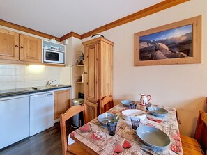 A kitchen with wooden cabinets, a microwave, and a dining area with a table set for two.