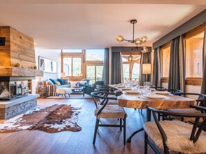 A spacious living area with a fireplace, wooden walls, and a dining table set for six. - Luxurious chalet, direct slope access, parking and WIFI included (Saint-Martin-de-Belleville)