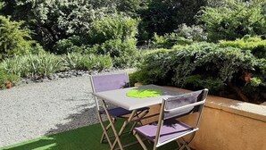 A foldable table and chairs set on artificial grass, surrounded by a gravel path and dense greenery. - 2 steps from the historic center, gite*** with beautiful saltwater swimming pool (Sarlat-la-Canéda)