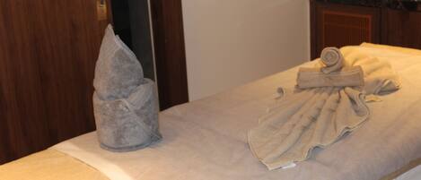 A hotel room with a massage table, towels, and a marble countertop.