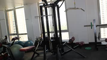 A gym with exercise equipment, large windows, and a view of buildings outside.
