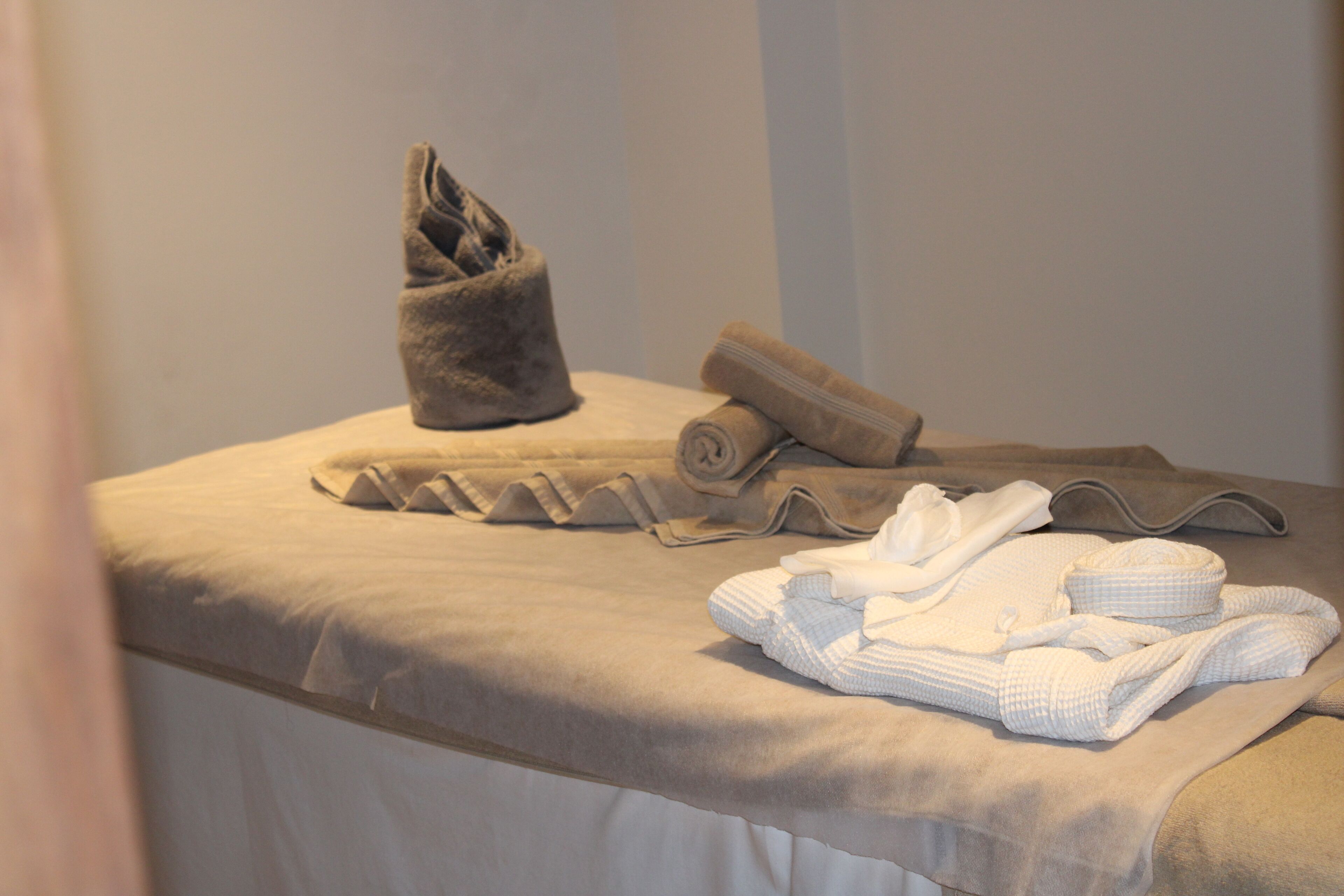 A neatly arranged bathroom with a towel rack, a rolled towel, and folded towels on a beige countertop.