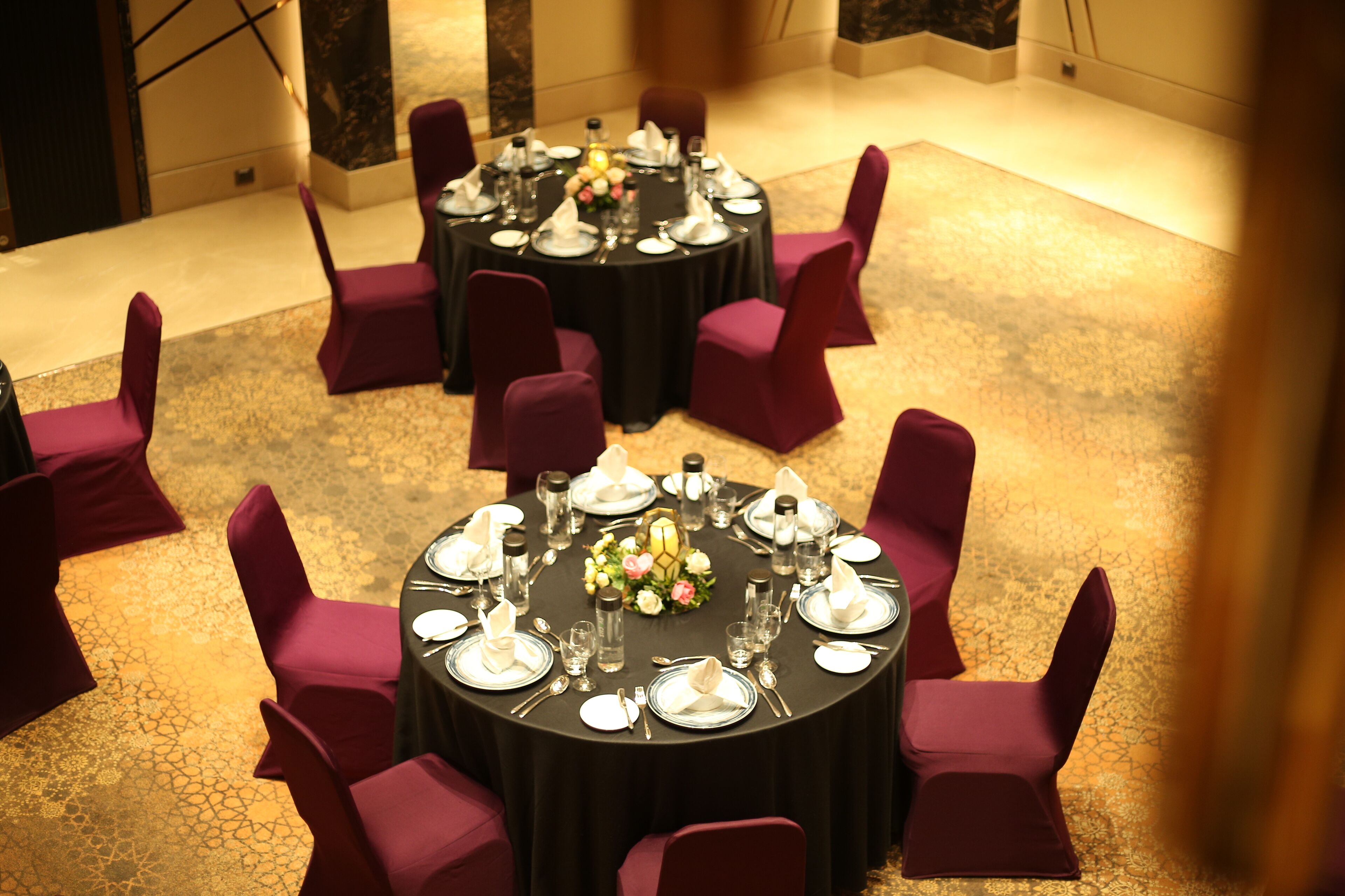 A conference room with two round tables set for a meeting, each surrounded by purple chairs.
