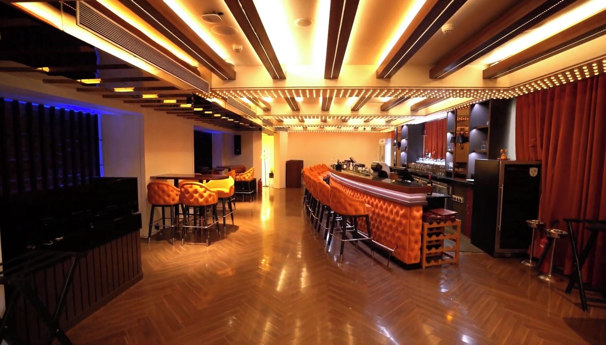 A bar area with wooden flooring, bar stools, and a bar counter.