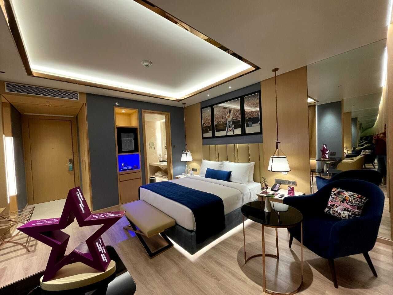 A modern hotel room with a bed, bedside tables, a desk, a chair, and a star-shaped decorative piece.